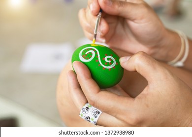 Hands that draw patterns and add color to the eggs. Easter concept.