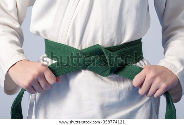 Hands tightening green belt on a teenage dressed\
in kimono