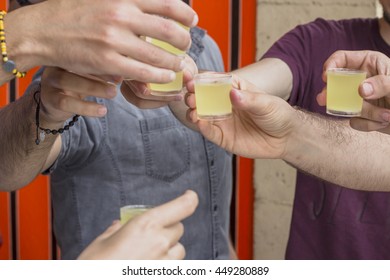 Hands toasting with shots during a party outdoors.