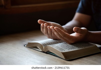 Hands together in prayer to God along with the bible In the Christian concept of faith, spirituality and religion, men pray in the Bible. prayer bible - Shutterstock ID 2139611731