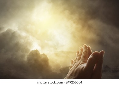 Hands together praying in bright sky