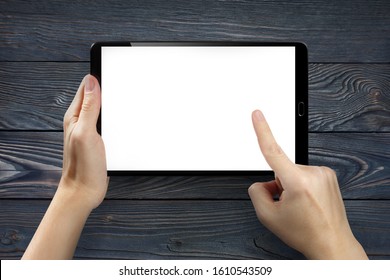 Hands touching blank screen of tablet computer on dark wooden background
