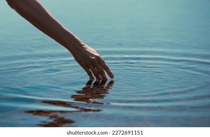 hands touching calm water making ripples	