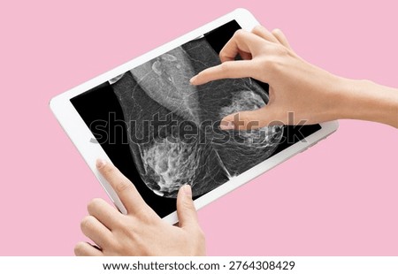 Hands touching digital tablet with breast cancer mammogram x-ray over pastel pink background for breast cancer awareness.