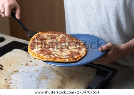 hands transferring pizza using spatula to parchmentlined tray, golden edges and bubbling cheese, handson meal prep, homemade comfort food moment