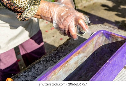 Hands With Transparent Gloves Using A Purple Paint Spray To Color A Rectangular Pot