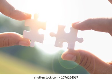 hands trying to connect couple puzzle piece with sky,sunset background. Business success and strategy concept - Shutterstock ID 1076164067