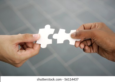 hands trying to fit two puzzle pieces together