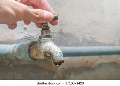 Hands Are Turning The Old Faucet Knob Connected The Blue Pvc Pipe To Close Running Water With Water Dripping Close-up.