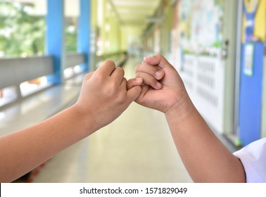 The Hands Of Two Children Hook Each Other's Little Finger