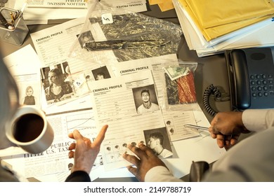 Hands of two interracial FBI agents pointing at profile of one of killers or other criminals while discussing personal information - Shutterstock ID 2149788719