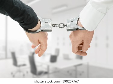 Hands Of Two Men Fixed In Handcuffs. Close Up. Blurred Office Background. Concept Of Accessory Of Crime.