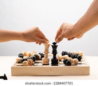 hands of two persons playing chess on wooden board on white background