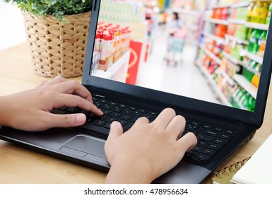 Hands typing labtop with blur supermarket on screen, grocery online concept, business and technology