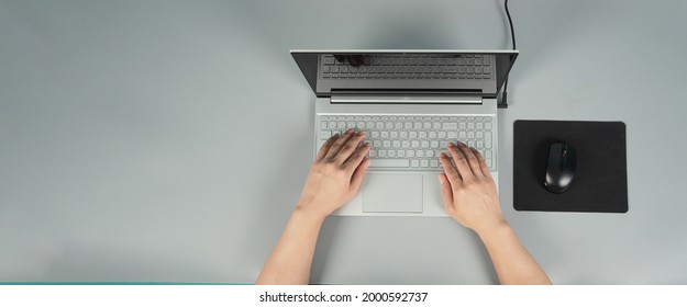 Hands Is Typing On Computer Laptop Or Notebook With Mouse And Pad On Grey Background.Studio Shot.top Eye View.