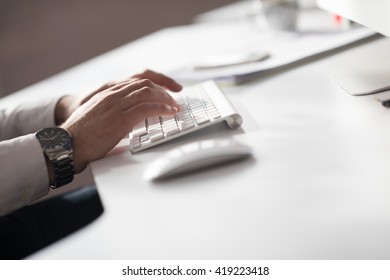hands typing on desktop computer keyboard in modern bright office interior