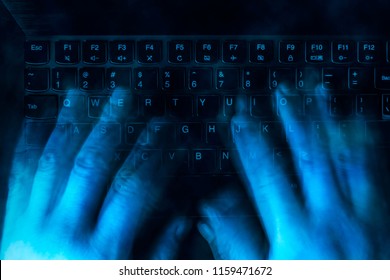 hands are typing on the keyboard in the dark. Blured