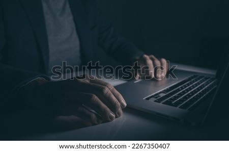 Hands typing on laptop keyboard. Man working on computer. Dark mood. Technology, business concept