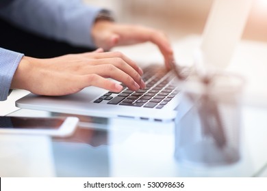 Hands typing text on a laptop keyboard