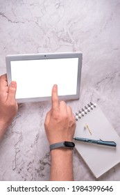 Hands of an unknown person using a tablet on a marble background.