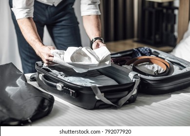 Hands of unrecognisable businessman packing his shirts in suitcase for business travel.