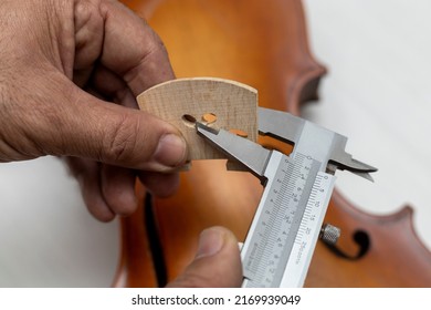 Hands of an unrecognizable Latin American luthier taking precise measurements of a violin bridge with a vernier. Concept stringed instruments