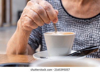 Hands Of Unrecognizable Older Woman Moving The Spoon In A Latte.