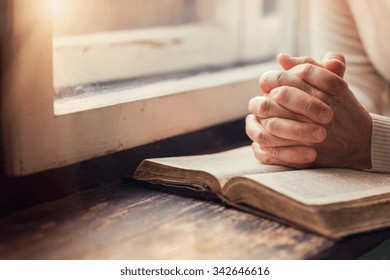Hands of an unrecognizable woman with Bible praying