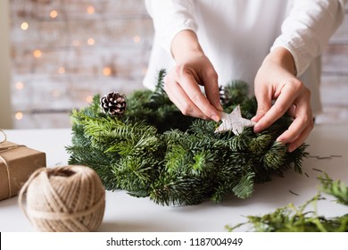 Hands of unrecognizable woman decorating christmas wreath.