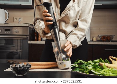 Hands of unrecognizable woman using blender to make smoothie