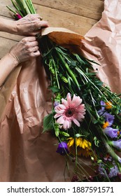 Hands Unwrapping Cut Flowers From Wrapping Paper