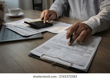 Hands using calculator on expense report document with pen performing financial calculation and reviewing budget data for accounting analysis and expense management on desk with laptop and paperwork