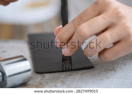 Hands Using Four Prong Pricking Iron on Leather
