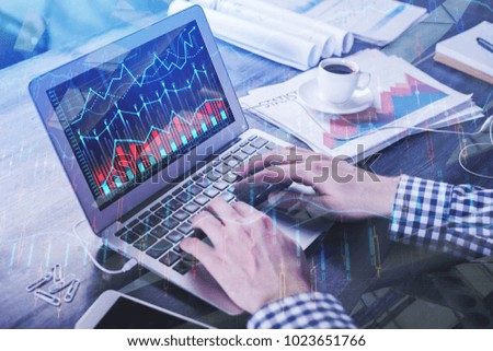 Hands using laptop with forex chart at workplace. Accounting and trade  concept. Double exposure 