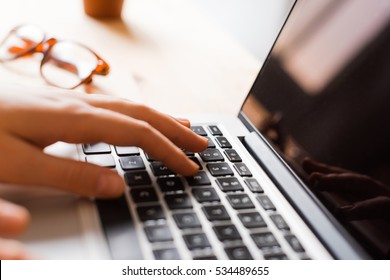 Hands using laptop type on keyboard, simple clean close up image with sun flare