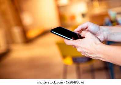 Hands Using Mobile Phone Apps And Online Communication, Internet, Reading Messages On Yellow Blurred Office Background. Copy Space