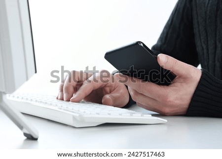 Man’s hands using PC and smart phone