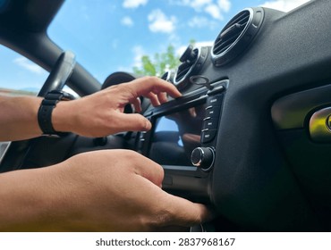 Hands using removal keys to pull car stereo from dashboard panel. Concept of car audio upgrade, auto electronics repair, vehicle installation, car service
