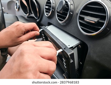 Hands using removal keys to pull car stereo from dashboard panel. Concept of car audio upgrade, auto electronics repair, vehicle installation, car service
