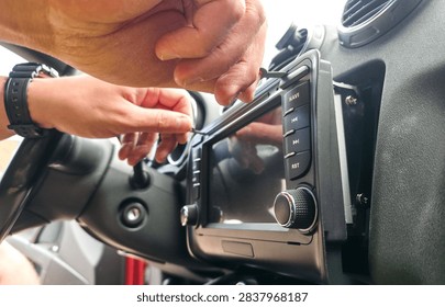 Hands using removal keys to pull car stereo from dashboard panel. Concept of car audio upgrade, auto electronics repair, vehicle installation, car service