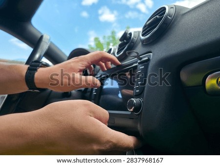 Hands using removal keys to pull car stereo from dashboard panel. Concept of car audio upgrade, auto electronics repair, vehicle installation, car service