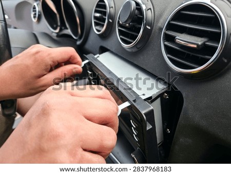 Hands using removal keys to pull car stereo from dashboard panel. Concept of car audio upgrade, auto electronics repair, vehicle installation, car service