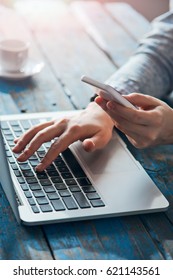 Hands using smart phone while person sitting at the computer