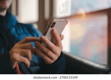 hands using smartphone indoors, browsing or texting with blurred background and warm light. Great for lifestyle, communication, technology, mobile app digital connection content.
