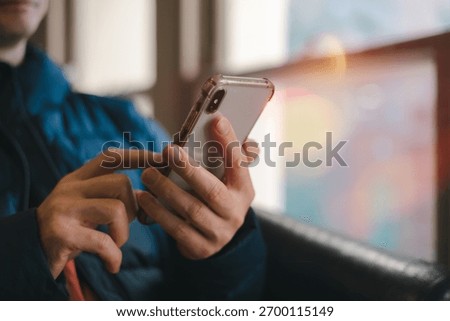 hands using smartphone indoors, browsing or texting with blurred background and warm light. Great for lifestyle, communication, technology, mobile app digital connection content.