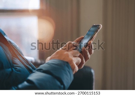 hands using smartphone indoors, browsing or texting with blurred background and warm light. Great for lifestyle, communication, technology, mobile app digital connection content.