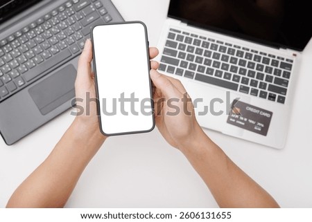 Hands using smartphone mockup on office desk. Blank screen mobile phone for graphic display montage
