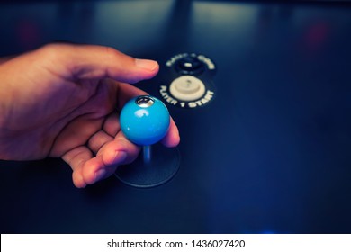 Hands of a video gamer holding a classic 4 way joystick with custom top fire modification and arcade buttons.