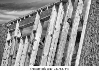 Hands Of Volunteers Raising A Wall For Habitat For Humanity Home