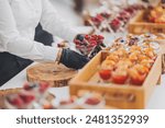 hands of a waiter prepare food for a buffet table in a restaurant. caterer arranges array of appetizers on a serving table. professional catering event with an emphasis on presentation and variety.